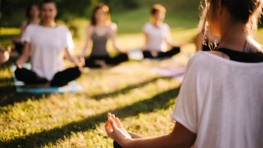 Yoga-Wiese Während eines Yogakurses führen die Teilnehmer Übungen auf einer Wiese durch.