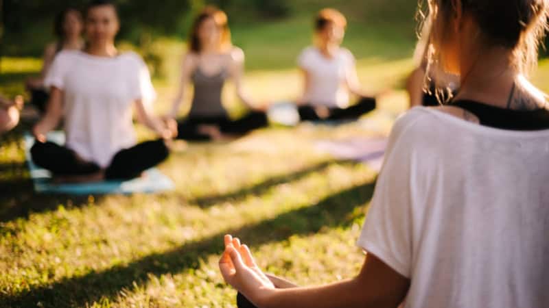 Während eines Yogakurses führen die Teilnehmer Übungen auf einer Wiese durch.