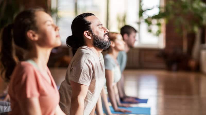 Vier Personen führen eine Yoga-Übung durch.