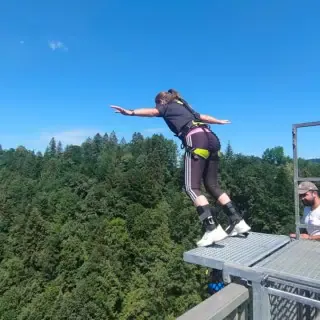 Frau Springt mit dem Bungee Seil von der Brücke