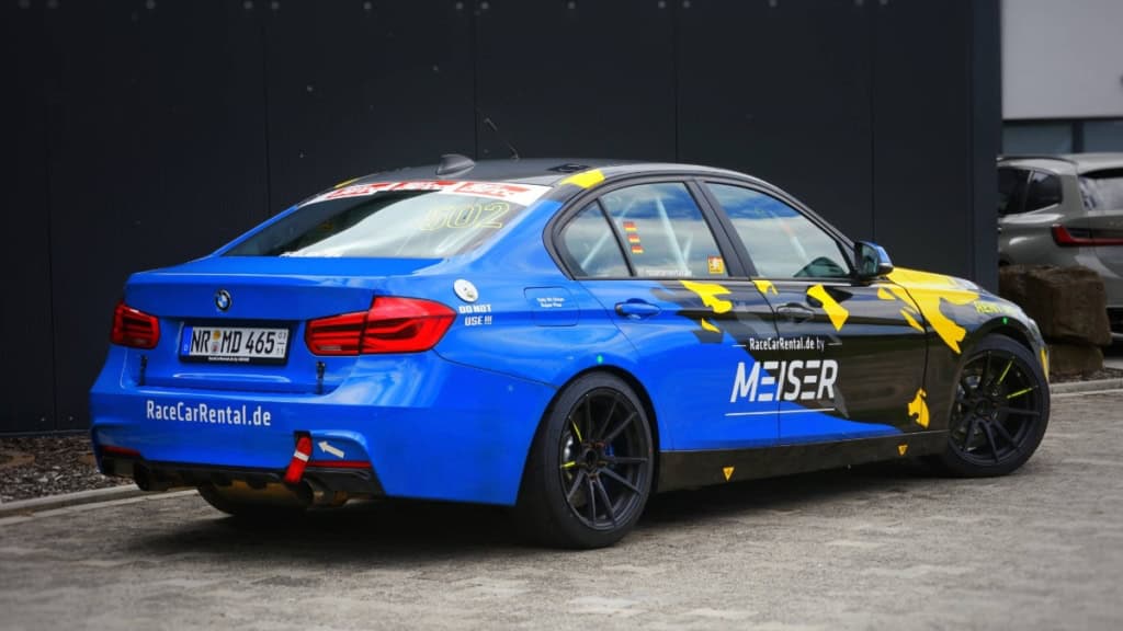 BMW F30 330i selber fahren - seitliche Ansicht Blau-schwarzer BMW F30 330i von hinten. Das Fahrzeug steht zur Abholung bereit. Selber fahren auf dem Nürburgring.