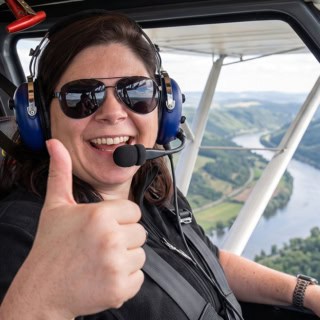 Person sitzt in einem Flugzeug bei einem Rundflug über Natur