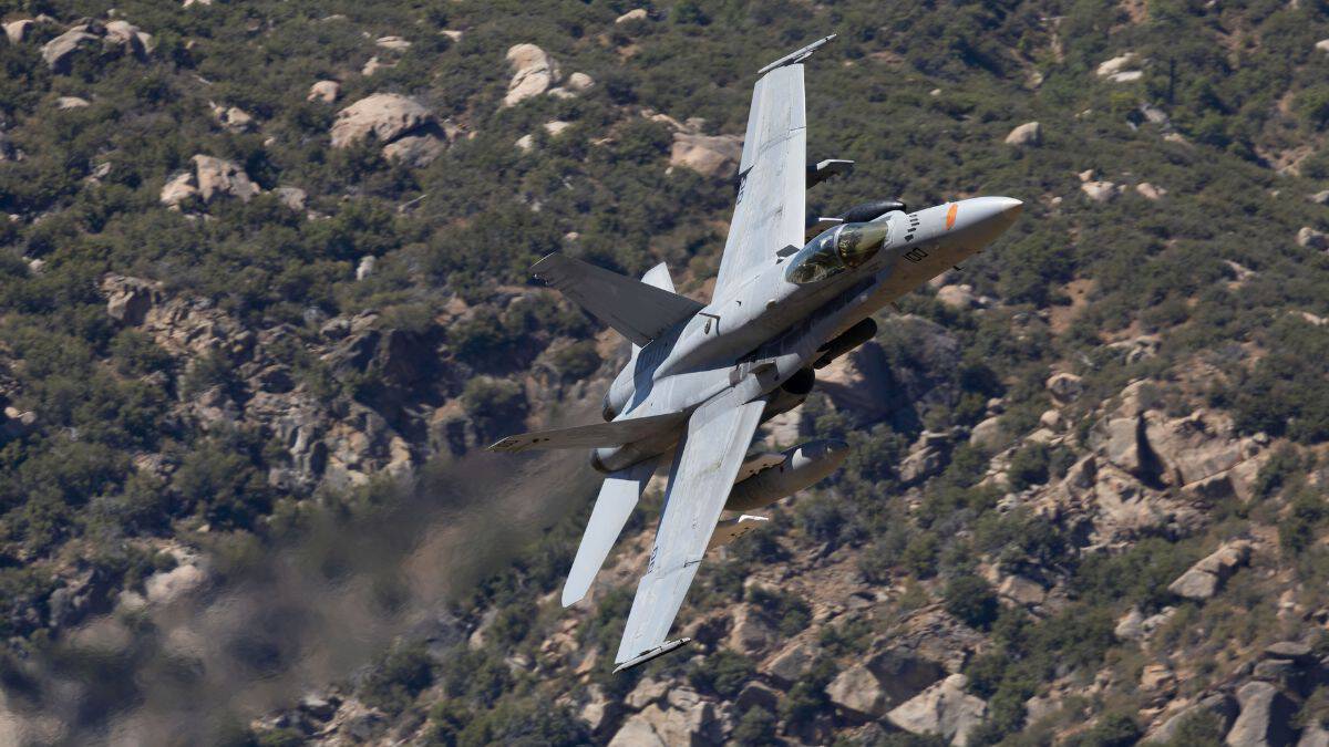 Kampfjet Superhornet F18 Kampfjet im Tiefflug über einer felsigen Landschaft.