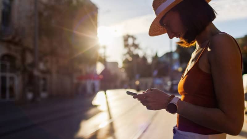 Ein Frau löst bei Sonnenaufgang mit dem Handy ein Rätsel - Digitale Stadtrallye.