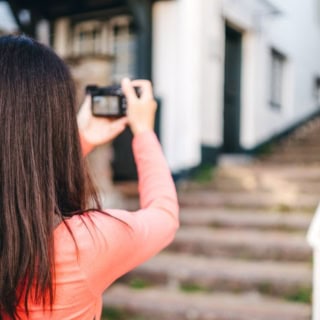 Eine Frau fotografiert mit eigener Kamera bei einem Fotokurs.