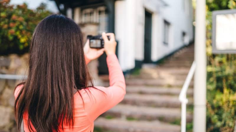 Eine Frau fotografiert mit eigener Kamera bei einem Fotokurs.