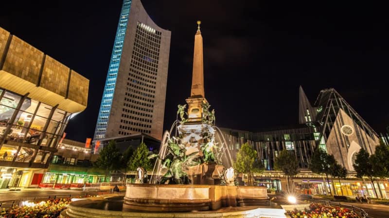 Erlebnisfabrik Stadtplatz bei Nacht Leipzig bei Nacht mit Brunnen, modernen Gebäuden und beleuchteten Sehenswürdigkeiten.