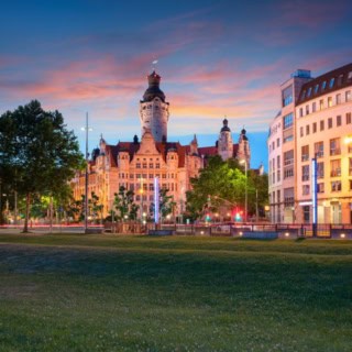 Historisches Stadtbild bei Sonnenuntergang mit alten Gebäuden im Hintergrund, beleuchtet und lebendig.