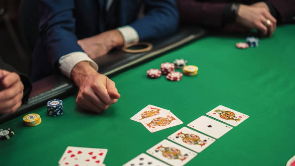 Poker-Karten aufgedeckt Drei Personen spielen Poker an einem grünen Tisch. Die Karten sind aufgedeckt, sodass der Gewinner ermittelt werden kann.