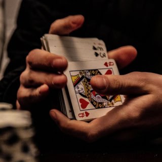 Ein Mann mischt Karten bei einer Pokerrunde.