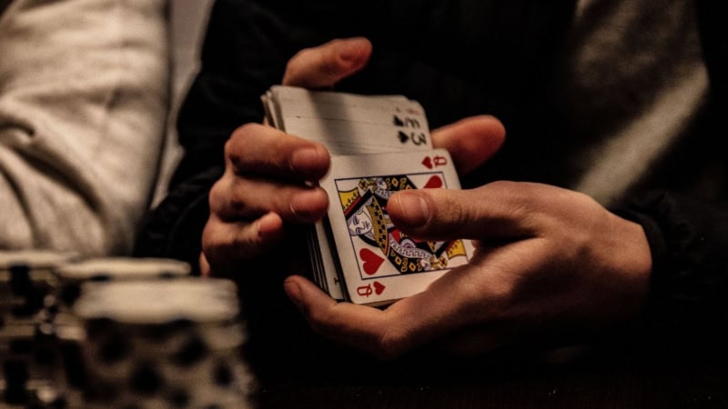 Ein Mann mischt Karten bei einer Pokerrunde.