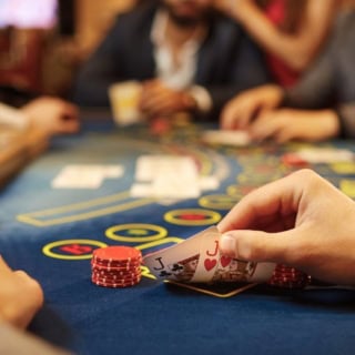 Ein Spieler schaut sich verdeckt seine Karten bei einer Pokerrunde an.