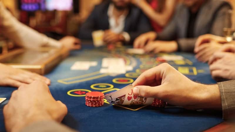 Ein Spieler schaut sich verdeckt seine Karten bei einer Pokerrunde an.