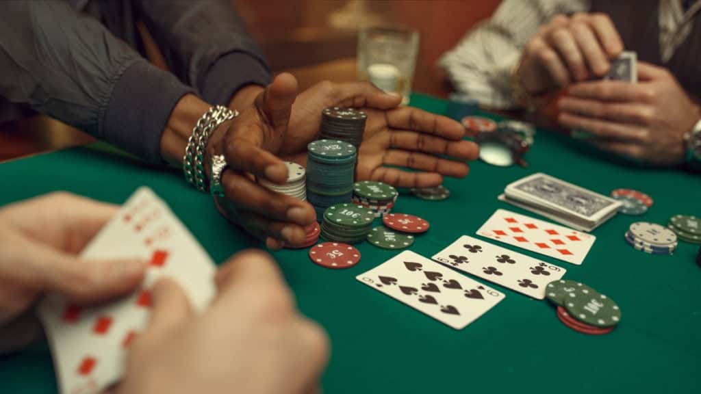 Poker-Runde mit 3 Spielern 3 Personen spielen Poker mit Chips und Karten auf einem grünen Tisch.