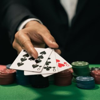 Der Dealer legt drei neunen auf den Pokertisch.