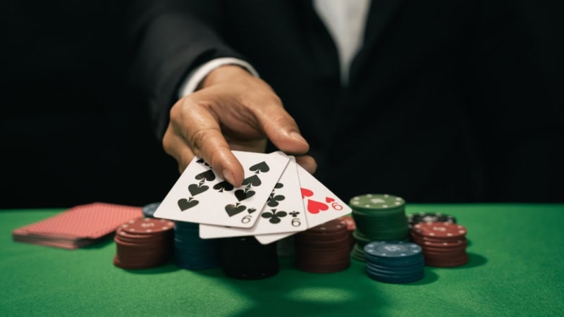 Der Dealer legt drei neunen auf den Pokertisch.