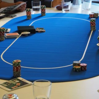 Neun Personen sitzen bei einem Pokerkurs Workshop an einem Pokertisch.