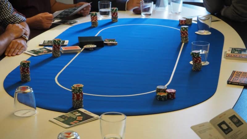 Neun Personen sitzen bei einem Pokerkurs Workshop an einem Pokertisch.